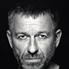 Sean Pertwee به عنوان John Moorcroft